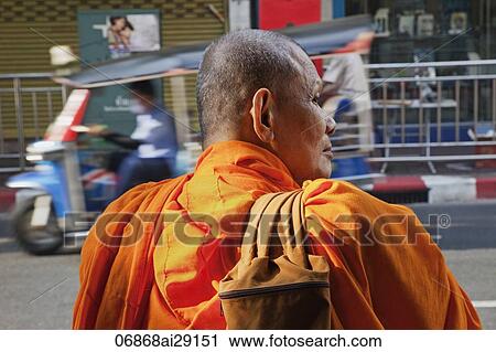 Stock Image - Rear view of Monk standing by side of road. Bangkok, Thailand. Fotosearch