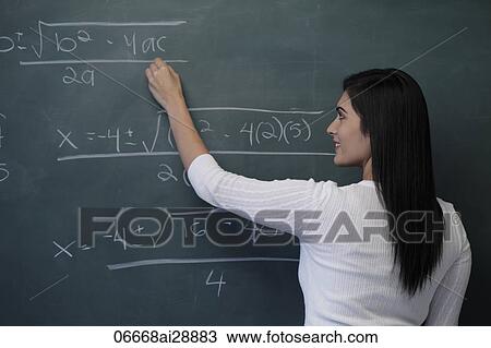 Stock Image - Rear view of young woman writing math equation on chalk board. Fotosearch