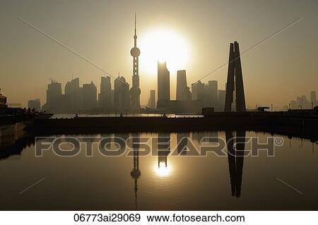 Stock Photo - Shanghai city skyline with People's Heroes War Memorial in foreground, reflected in water at sunrise. China. Fotosearch