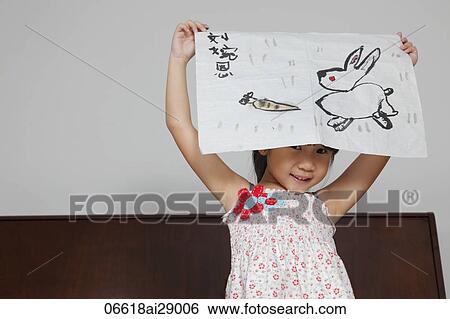 Young Chinese girl smiling holding up picture of rabbit View Large Photo Image Stock Photograph - Young Chinese girl smiling holding up picture of rabbit. Fotosearch