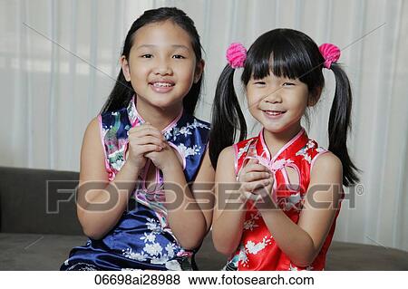 Stock Photo - Young Chinese girls holding hands together in greeting. Fotosearch