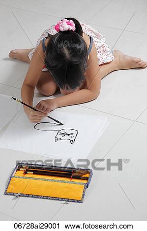 Stock Image - Young girl drawing a cat with Chinese brush and ink. Fotosearch