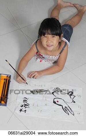 Picture - Young girl laying on floor drawing pictures with Chinese brush and ink. Fotosearch