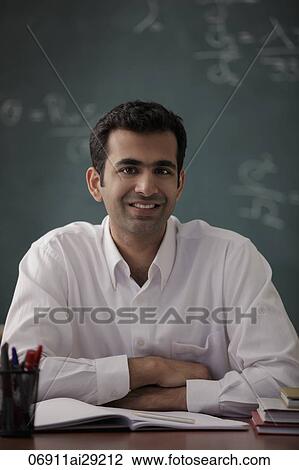 Young man sitting at his desk smiling View Large Photo Image Stock Image - Young man sitting at his desk smiling. Fotosearch