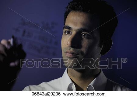 Stock Photograph - Young man writing on transparent glass wall.. Fotosearch