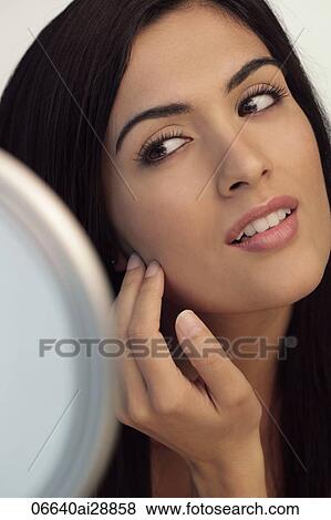 Young woman touching her face while looking at mirror. View Large Photo Image Stock Photo - Young woman touching her face while looking at mirror.. Fotosearch