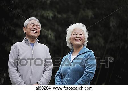 A senior couple in sweatsuits laughing outdoors View Large Photo Image Picture - A senior couple in sweatsuits laughing outdoors. Fotosearch