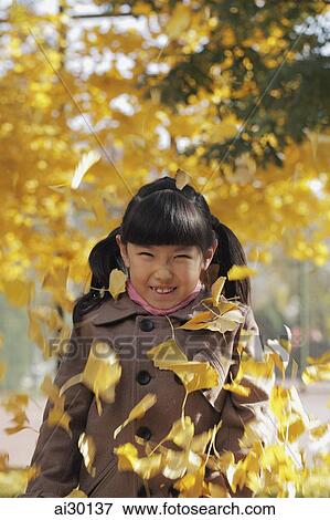 Autumn leaves falling on young girl View Large Photo Image Stock Photo - Autumn leaves falling on young girl. Fotosearch