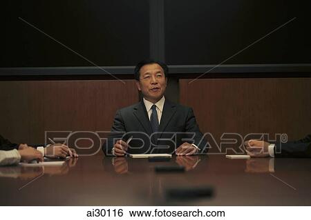 Businessman sitting at head of the table View Large Photo Image Stock Photograph - Businessman sitting at head of the table. Fotosearch