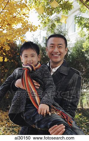 Stock Image - Dad holding his son outdoors. Fotosearch