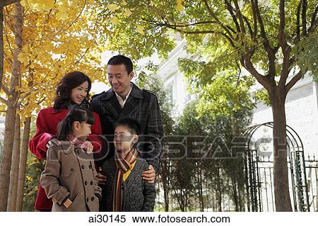Family of four standing together in front of their home View Large Photo Image Stock Photography - Family of four standing together in front of their home. Fotosearch