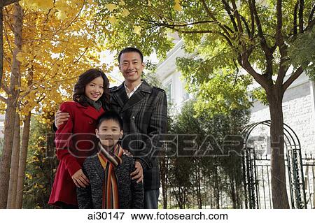 Stock Photo - Family with young boy standing in front of their house. Fotosearch