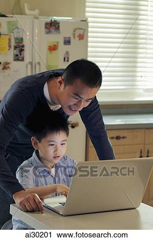 Stock Image - Father and son working on laptop computer together. Fotosearch