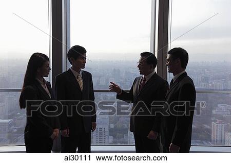 Four businesspeople talking in front of a window View Large Photo Image Stock Image - Four businesspeople talking in front of a window. Fotosearch