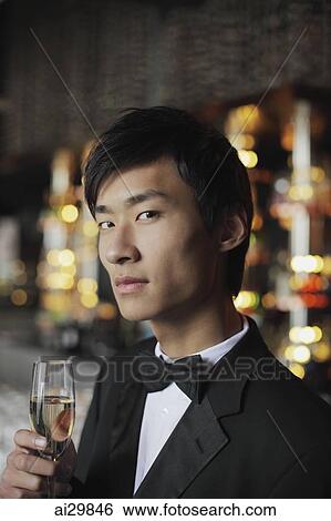 Stock Photograph - Head shot of man in a tuxedo holding a glass of champagne. Fotosearch