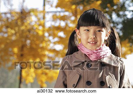 Stock Image - Head shot of young girl wearing a coat outdoors. Fotosearch