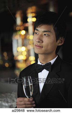 Head shot of young man wearing a tuxedo and holding a glass of champagne View Large Photo Image Stock Photo - Head shot of young man wearing a tuxedo and holding a glass of champagne. Fotosearch