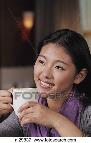 Stock Photo - Head shot of young woman holding coffee cup. Fotosearch