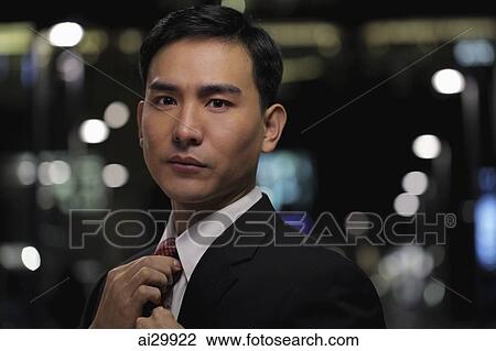 Man in business suit straightening his tie at night View Large Photo Image Stock Image - Man in business suit straightening his tie at night. Fotosearch