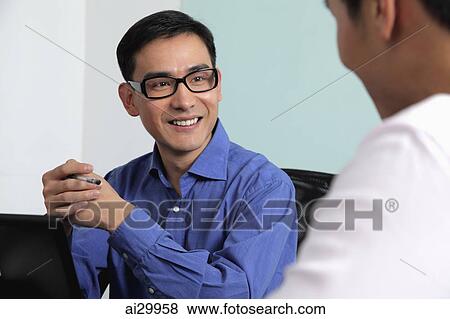 Man smiling at another man during meeting View Large Photo Image Stock Photo - Man smiling at another man during meeting. Fotosearch
