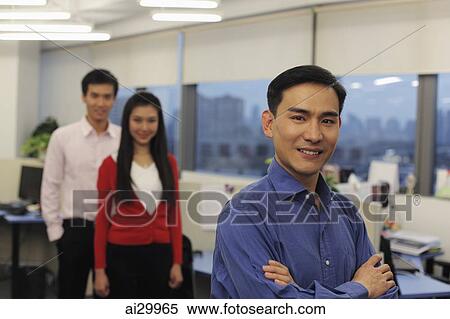 Man standing in front of his colleagues in an office View Large Photo Image Stock Photography - Man standing in front of his colleagues in an office. Fotosearch