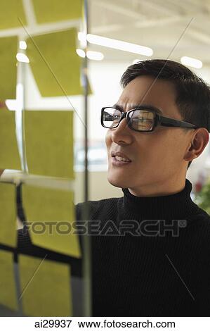 Man wearing glasses looking at stick on notes View Large Photo Image Stock Photo - Man wearing glasses looking at stick on notes. Fotosearch