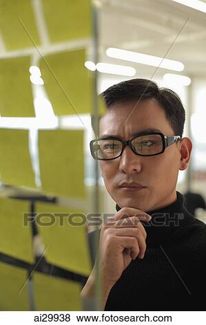 man wearing glasses looking at stick on notes View Large Photo Image Stock Photo - man wearing glasses looking at stick on notes. Fotosearch