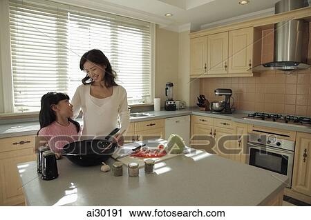 Mother and daughter cooking food together in the kitchen View Large Photo Image Stock Image - Mother and daughter cooking food together in the kitchen. Fotosearch