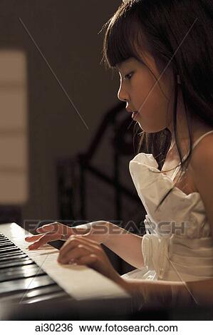 Stock Photograph - Profile of young girl playing piano. Fotosearch