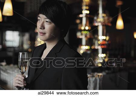 Profile of young man holding a glass of champagne. View Large Photo Image Picture - Profile of young man holding a glass of champagne.. Fotosearch