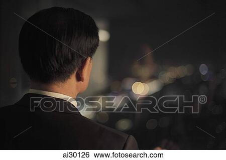 Rear view of businessman looking out of a window View Large Photo Image Stock Photograph - Rear view of businessman looking out of a window. Fotosearch