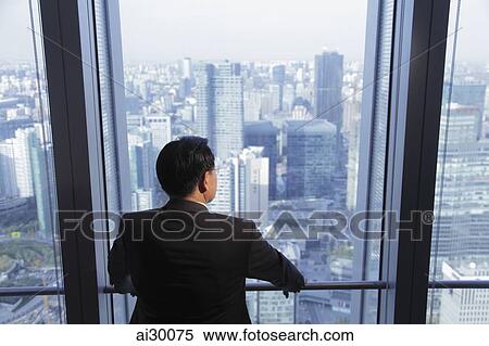 Rear view of man looking out the window at a city view, Beijing, China View Large Photo Image Stock Photography - Rear view of man looking out the window at a city view, Beijing, China. Fotosearch
