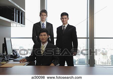 Stock Photo - Three businessmen standing together in an office. Fotosearch