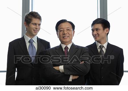 Stock Image - Three businessmen standing together. Fotosearch