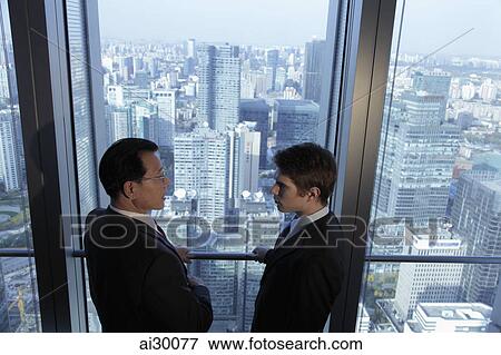 Two men talking in front of window with a view of the city of Beijing View Large Photo Image Stock Photo - Two men talking in front of window with a view of the city of Beijing. Fotosearch