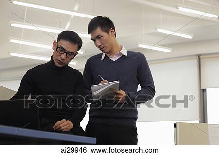 Two men working together in an office View Large Photo Image Stock Photograph - Two men working together in an office. Fotosearch