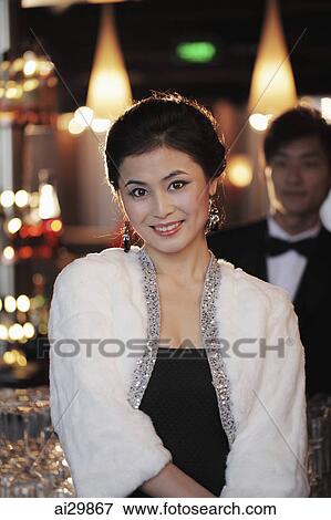 Woman dressed up at night with man in tuxedo in background View Large Photo Image Stock Photo - Woman dressed up at night with man in tuxedo in background. Fotosearch