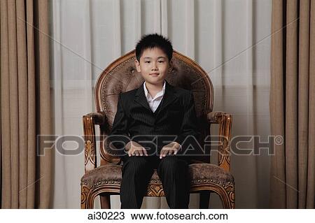 Young boy dressed up in suit sitting on a nice chair View Large Photo Image Stock Image - Young boy dressed up in suit sitting on a nice chair. Fotosearch