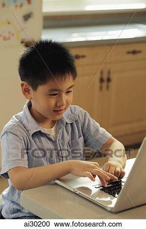Young boy playing on a lap top computer in the kitchen View Large Photo Image Stock Image - Young boy playing on a lap top computer in the kitchen. Fotosearch