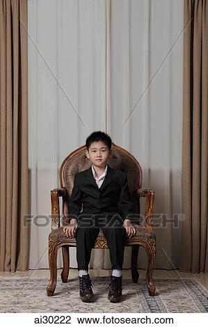 Young boy wearing suit sitting on nice chair View Large Photo Image Stock Image - Young boy wearing suit sitting on nice chair. Fotosearch