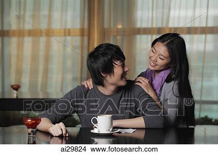 Picture - Young couple at cafe looking at each other. Fotosearch