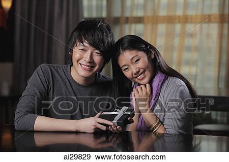 Young couple holding a present and smiling View Large Photo Image Stock Photo - Young couple holding a present and smiling. Fotosearch