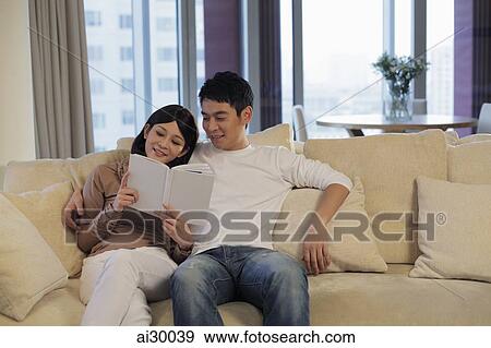 Young couple in living room reading a book together View Large Photo Image Stock Photo - Young couple in living room reading a book together. Fotosearch