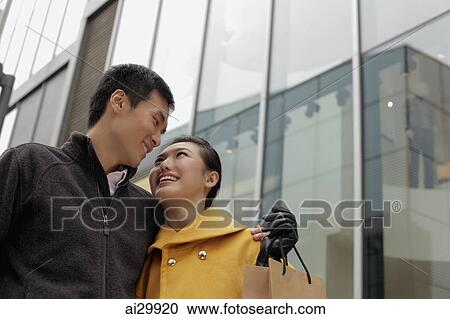 Stock Image - Young couple looking at each other while shopping. Fotosearch