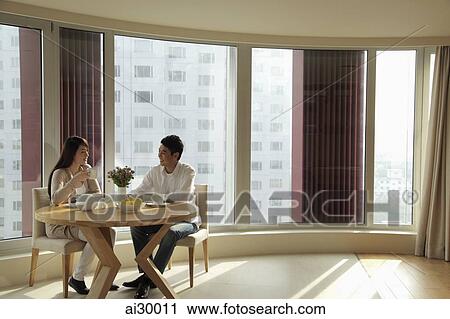 Young couple sitting at table in their spacious condo View Large Photo Image Stock Image - Young couple sitting at table in their spacious condo. Fotosearch