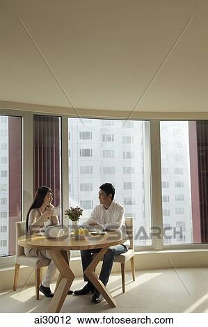 Young couple sitting at table in their condo View Large Photo Image Stock Image - Young couple sitting at table in their condo. Fotosearch