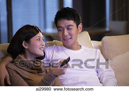 Young couple sitting on sofa watching TV together View Large Photo Image Stock Image - Young couple sitting on sofa watching TV together. Fotosearch
