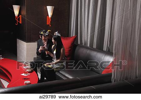 Young couple sitting together at a club drinking View Large Photo Image Stock Photo - Young couple sitting together at a club drinking. Fotosearch