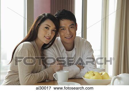 Stock Photo - Young couple sitting together in their home. Fotosearch