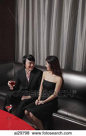 Young couple sitting together on sofa smiling at each other View Large Photo Image Stock Photo - Young couple sitting together on sofa smiling at each other. Fotosearch